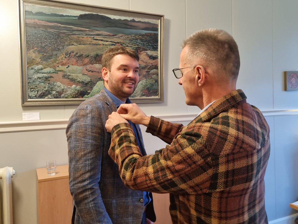 Skólameistari veitir Ásmundi Einari, ráðherra barna- og menntamála, gullugluna, heiðursmerki skólans