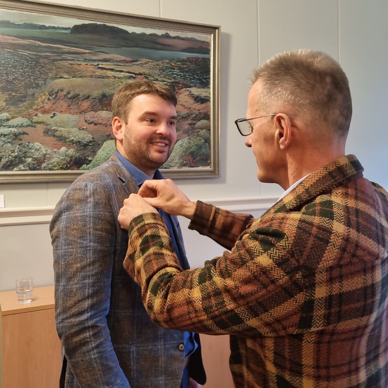 Skólameistari veitir Ásmundi Einari, ráðherra barna- og menntamála, gullugluna, heiðursmerki skólans